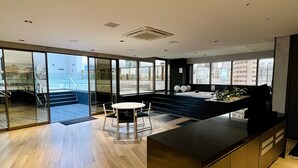 Una cocina moderna con una isla grande, un comedor con mesa y sillas, y ventanas amplias que ofrecen vistas de la ciudad.