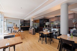 A spacious restaurant with wooden flooring, black chairs, and a bar area with stools. - Garner Hotel Friedrichshafen By IHG (Friedrichshafen)