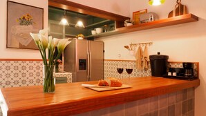 A kitchen with a wooden countertop, a refrigerator, a coffee machine, and a vase with flowers.