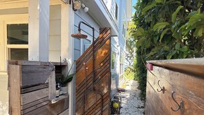 Una verja de madera que da a una casa con un grifo de agua a la vista y un pequeño jardín.