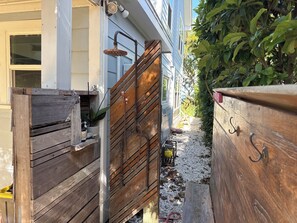 A wooden gate leading to a house with a visible water spigot and a small garden area. - Cozy 3BR Double Gallery Bayfront Cottage in Magical Old SE St. Petersburg (St. Petersburg)