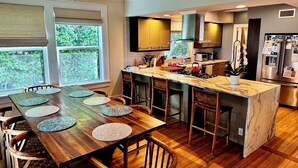 Una cocina moderna con una mesa de comedor de madera, taburetes de bar y una isla integrada.
