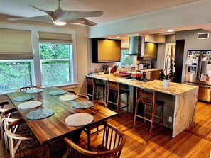 A modern kitchen with a wooden dining table, bar stools, and a built-in island. - Cozy 3BR Double Gallery Bayfront Cottage in Magical Old SE St. Petersburg (St. Petersburg)