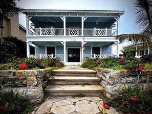 A two-story building with a porch, a flag, and a year number '1923' on the front door. - Cozy 3BR Double Gallery Bayfront Cottage in Magical Old SE St. Petersburg (St. Petersburg)