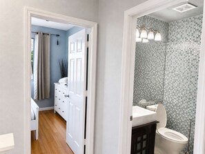 A bathroom with a tiled shower wall, a toilet, and a sink.