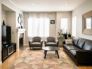 A living room with a fireplace, two armchairs, a sofa, a TV, and a coffee table.