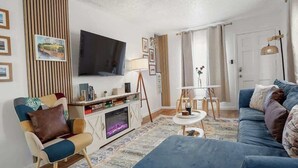 Olohuone, jossa on sohva, nojatuoli, televisio ja takka.