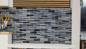 Een moderne keuken met een witte tafel, houten kastjes en een zwart-wit tegelachtergrond.