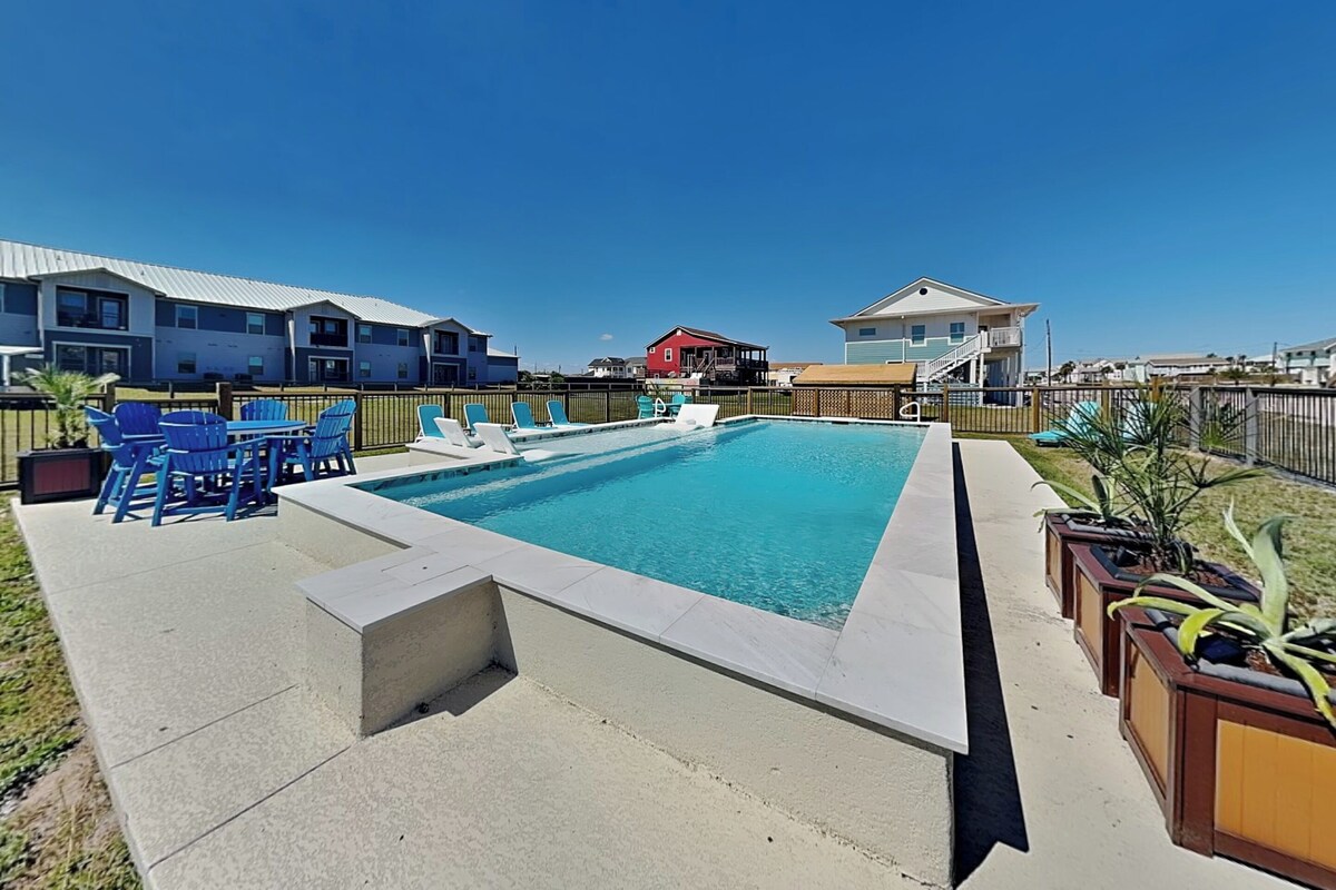 A rectangular swimming pool with a small deck area, surrounded by a fence.