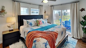A bedroom with a large bed, a ceiling fan, and a view of the outdoors. - Inn at Sea La Vie (Rockport)