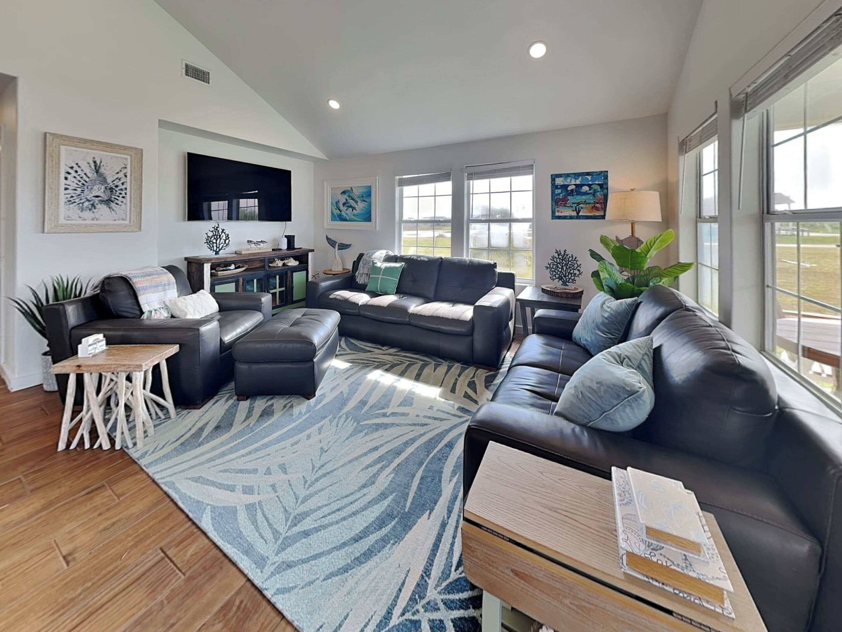A spacious living room with a large sectional sofa, a coffee table, and a TV mounted on the wall.