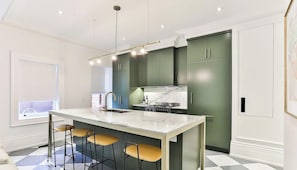 A modern kitchen with a central island, bar stools, and a built-in stove.