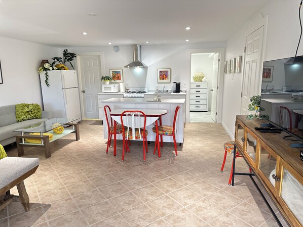 Una cucina moderna con mobili bianchi, un'isola centrale, sedie rosse e un tavolo da pranzo.