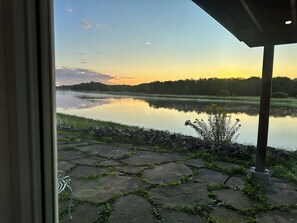 Une terrasse en pierre mène à un lac paisible, dont l’horizon est bordé d’une forêt.
