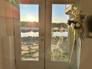 Puerta con vista a un lago y una silla afuera.