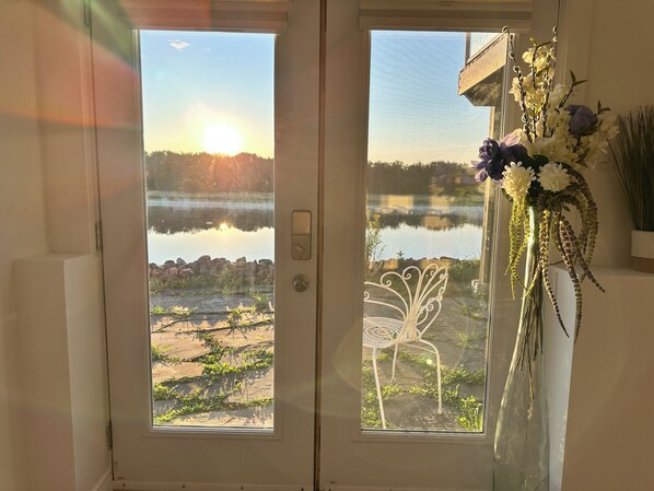 A door with a view of a lake and a chair outside. - On The Rocks Gagetown Serenity gorgeous waterfront on the Saint John River (Gagetown)