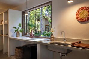 A modern kitchen with a large window, a sink, and a wooden stool.