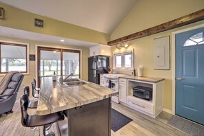 A kitchen with a central island, a refrigerator, a microwave, and a blue door.