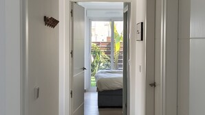 Un couloir étroit mène à une chambre à coucher qui contient un lit, une porte sur la droite et une porte sur la gauche.