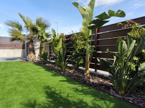 A well-maintained garden with various tropical plants, a neatly trimmed lawn, and a wooden fence. - Casa Juanita with pool (Torremendo)