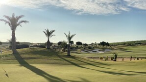 Un parcours de golf avec des bunkers de sable, des palmiers et un mât de drapeau.