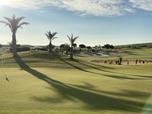 A golf course with sand bunkers, palm trees, and a flagstick. - Casa Juanita with pool (Torremendo)