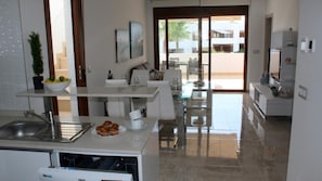 Una cocina moderna con comedor, vistas al exterior y una planta pequeña en la encimera.