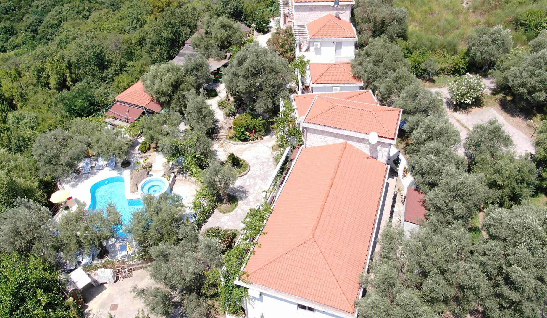 An aerial view of a resort with multiple buildings, a swimming pool, and surrounding greenery.