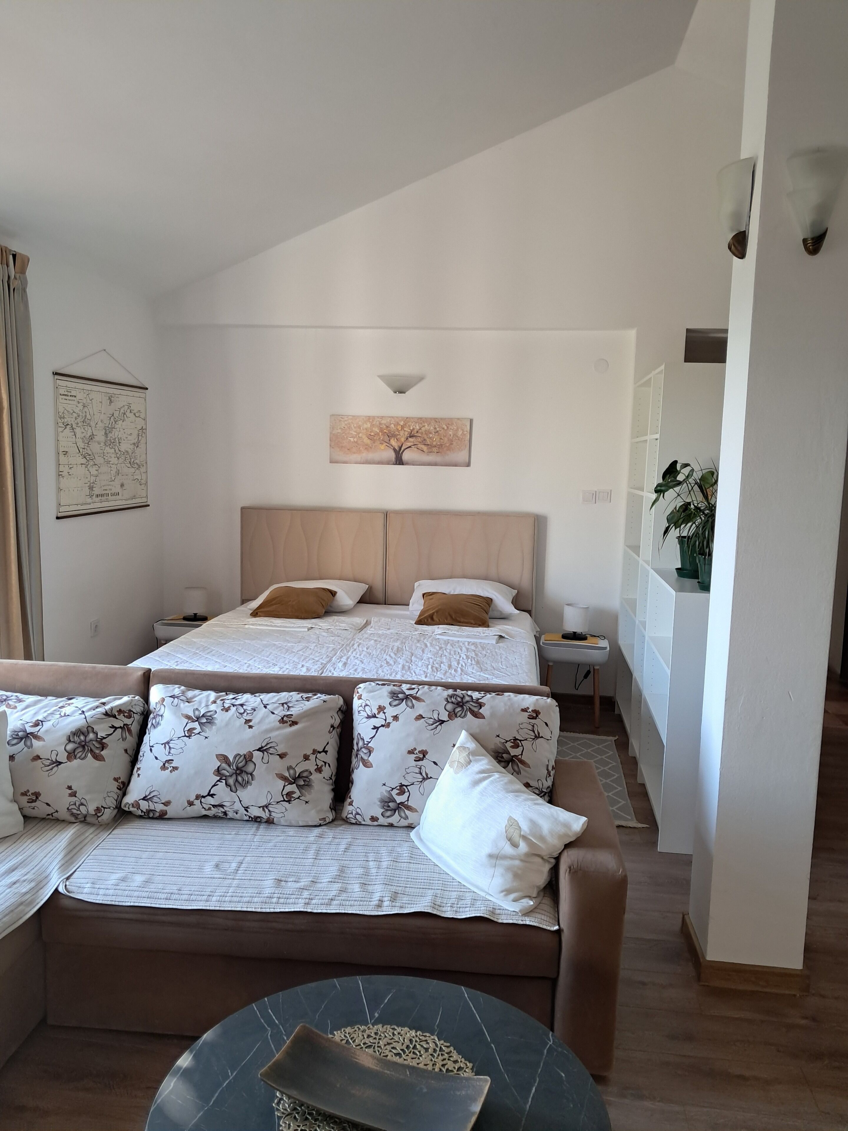 Un dormitorio con dos camas, un sofá, un mapa y una planta.