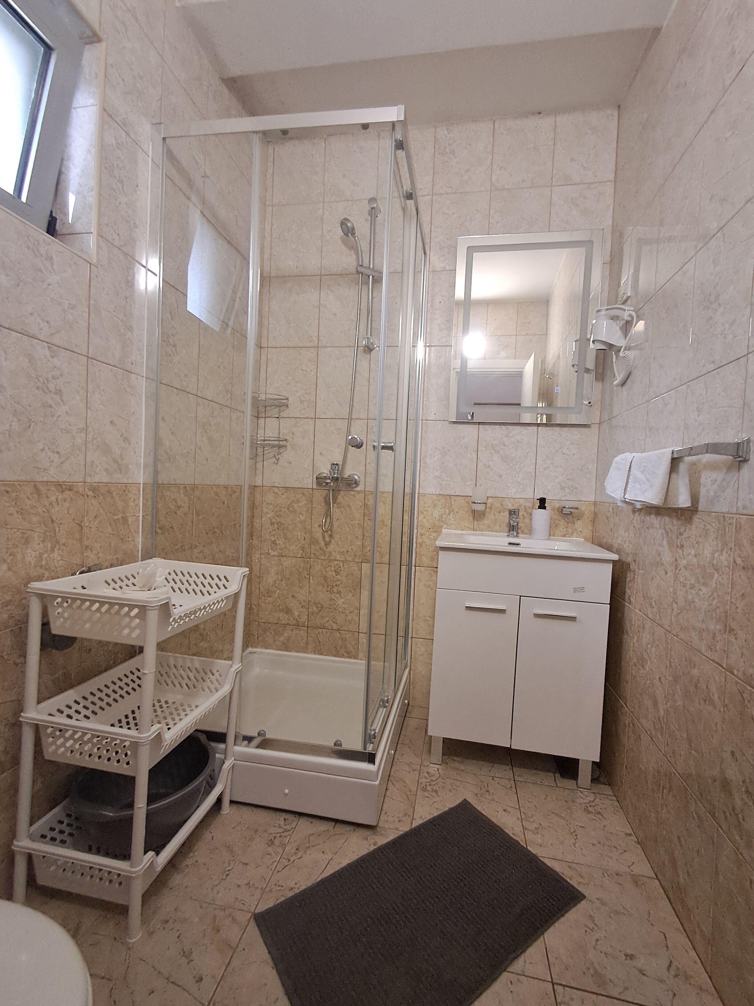 A bathroom with a glass-enclosed shower, a white sink, a mirror, and a white cabinet.