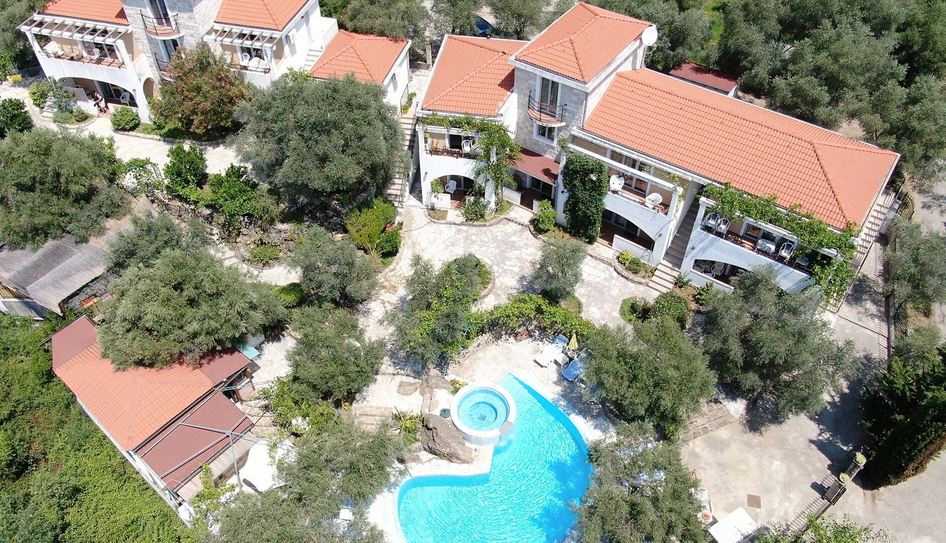Zona residencial con varias casas, piscina y abundante vegetación.