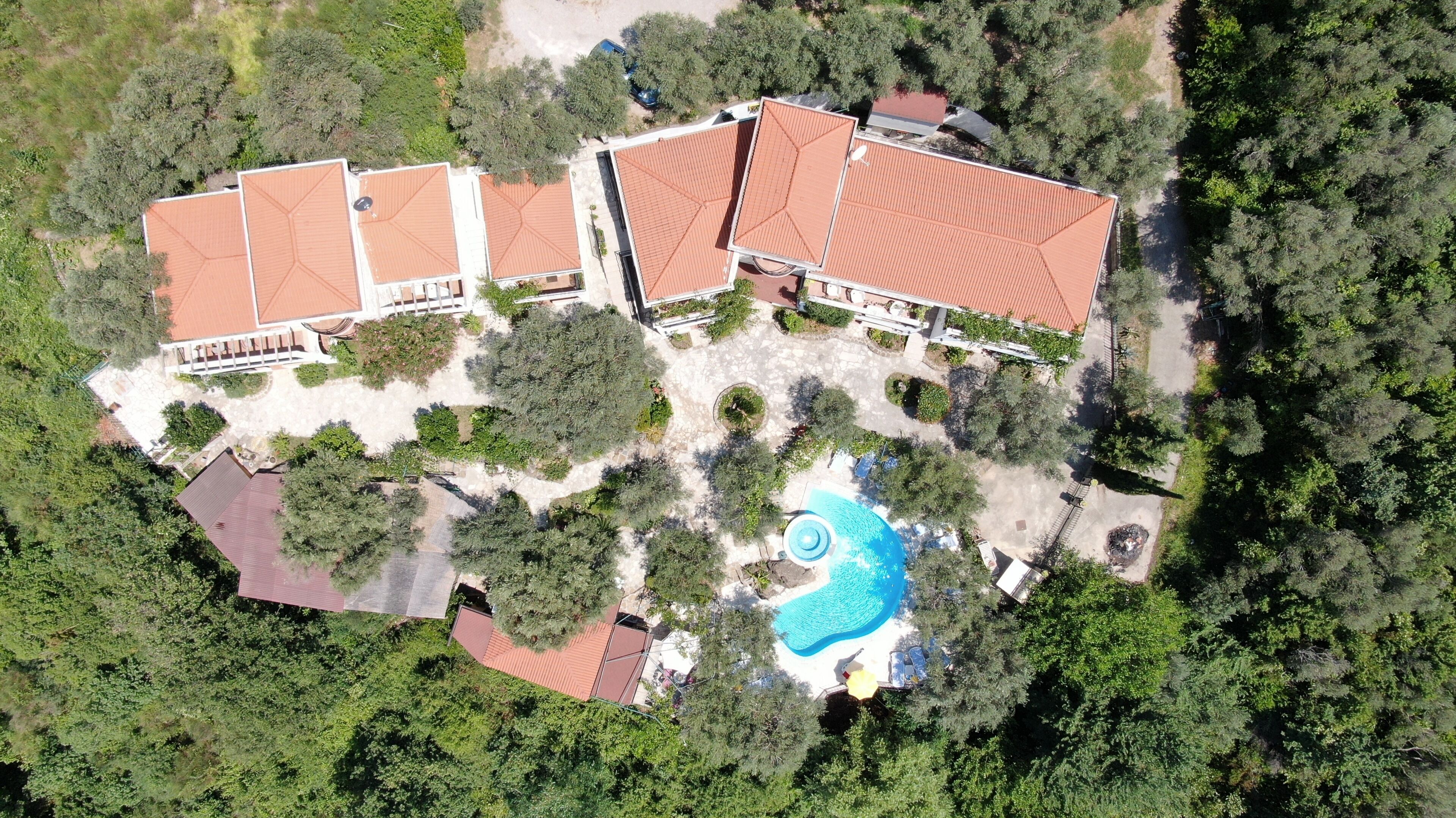 Une vue aérienne d’un complexe hôtelier comprenant plusieurs bâtiments, une piscine et une végétation luxuriante.