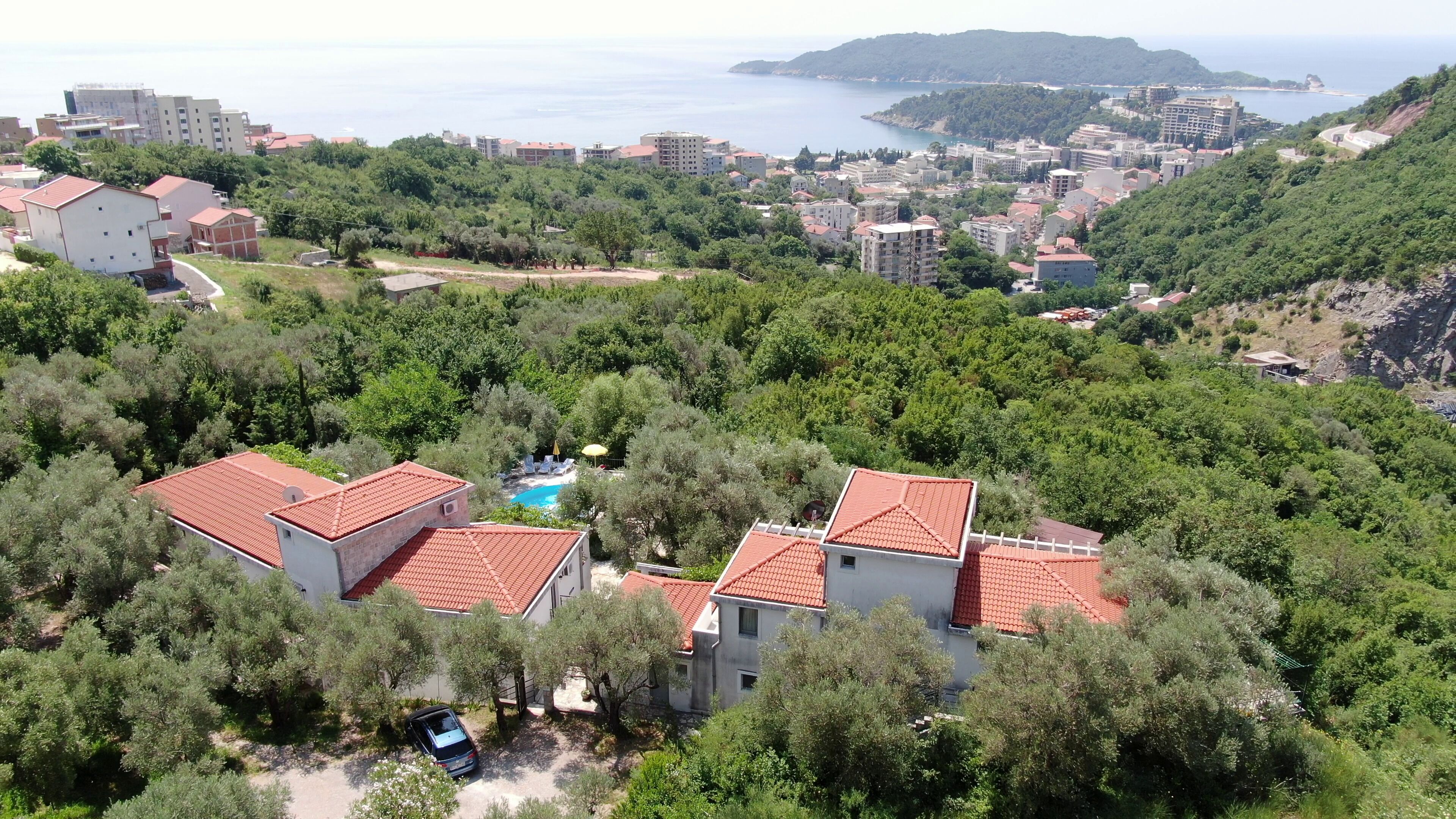 A residential area with houses, a swimming pool, and a view of the sea.
