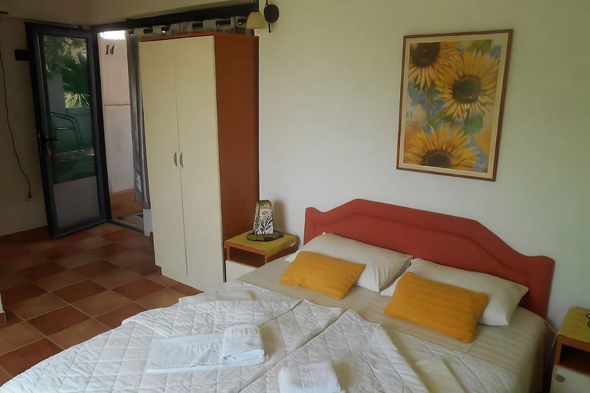 A bedroom with a bed, a wardrobe, a nightstand, a painting, and a door.