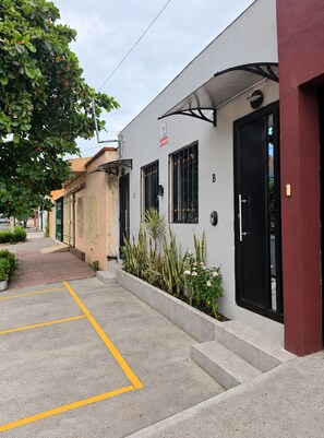 A building with a black door, a sign with a red border, and a paved area with yellow lines.