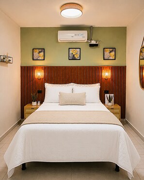 Ein Hotelzimmer mit einem großen Bett, einer Wandklimaanlage und zwei Nachttischlampen.