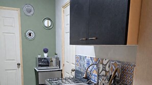 Una cucina compatta con lavello, fornello e pensili.