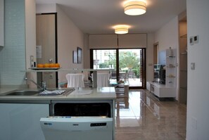 A modern kitchen with a dishwasher, a dining area with a table and chairs, and a view of the outside. - Ground floor Secreto La Zenia (La Zenia)