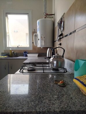 Une cuisine équipée d’une cuisinière à gaz, d’une bouilloire et d’un chauffe-eau.