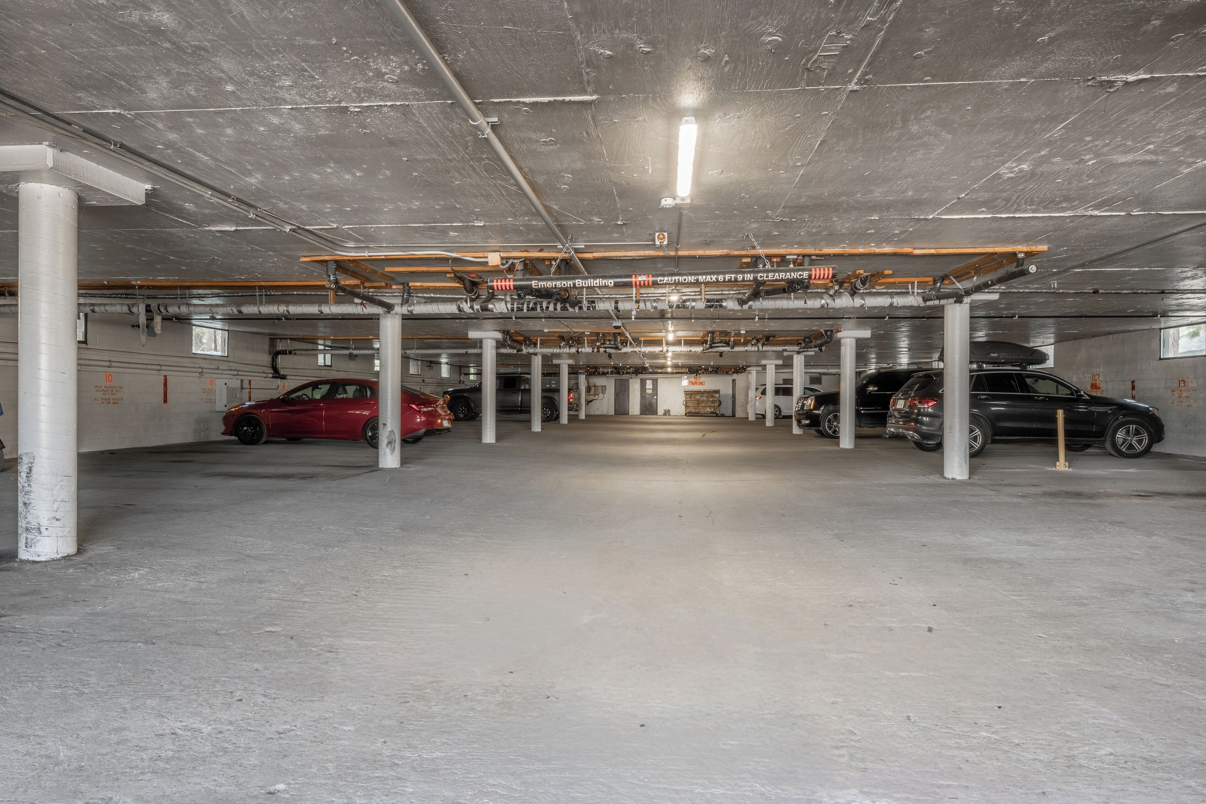 A multi-level parking garage with concrete floors and columns, featuring several parked cars.