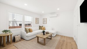 En moderne stue med en hvid sofa, et træbord og et lille sidebord med en plante.