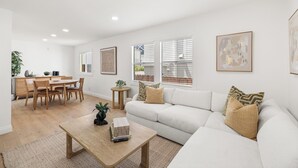 En moderne stue med sofa, sofabord, spisebord og stole.