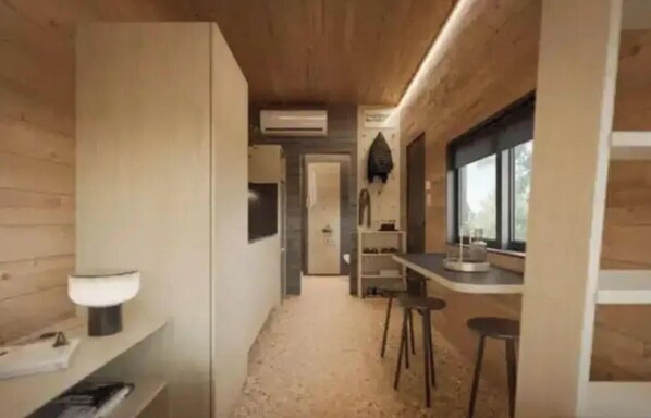 A narrow hallway with a toilet, a sink, and a bar area with stools.