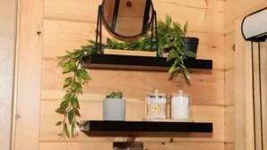 A wooden interior with shelves holding plants, a mirror, and storage containers. - “At 84 Ranch, a place to rest, reconnect, and remember what’s real.” (Pagosa Springs)