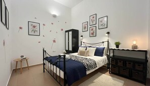 A bedroom with a bed, bedside table, lamp, wall decorations, and a wardrobe. - Traditional Stone House in Malonas (Rhodes)