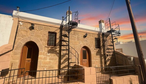 A stone building with three arched doorways and a spiral staircase. - Traditional Stone House in Malonas (Rhodes)