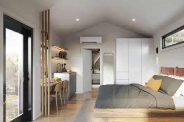 A compact room with a bed, a kitchenette, and a dining area.