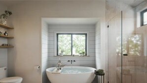 A bathroom with a freestanding bathtub, a window, and a glass shower enclosure. - “More than a stay-84 Ranch is a connection to the land, the animals, and what truly matters.” (Pagosa Springs)