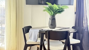A dining area with a table, chairs, a potted plant, and a flat-screen TV mounted on the wall. - Stylish studio apartment near the Olma trade fair (St. Gallen)