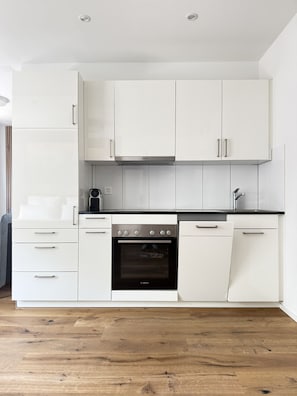 Een moderne keuken met witte kastjes, een Bosch oven en een zwart aanrecht.